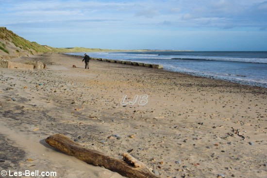 Dog walker on the beach at Druridge Bay, Northumberland.
